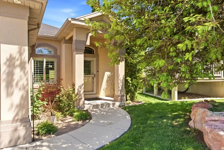 Doorway to property with a lawn, stucco siding, and a shingled roof