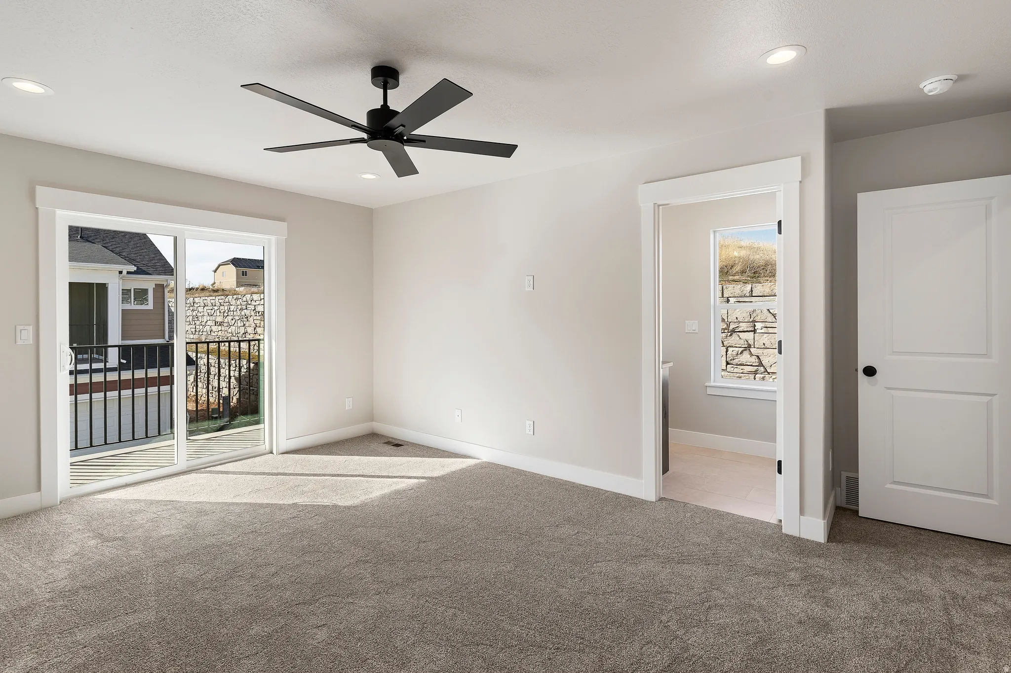 Spacious room featuring neutral carpet flooring, recessed lighting, and a modern black ceiling fan