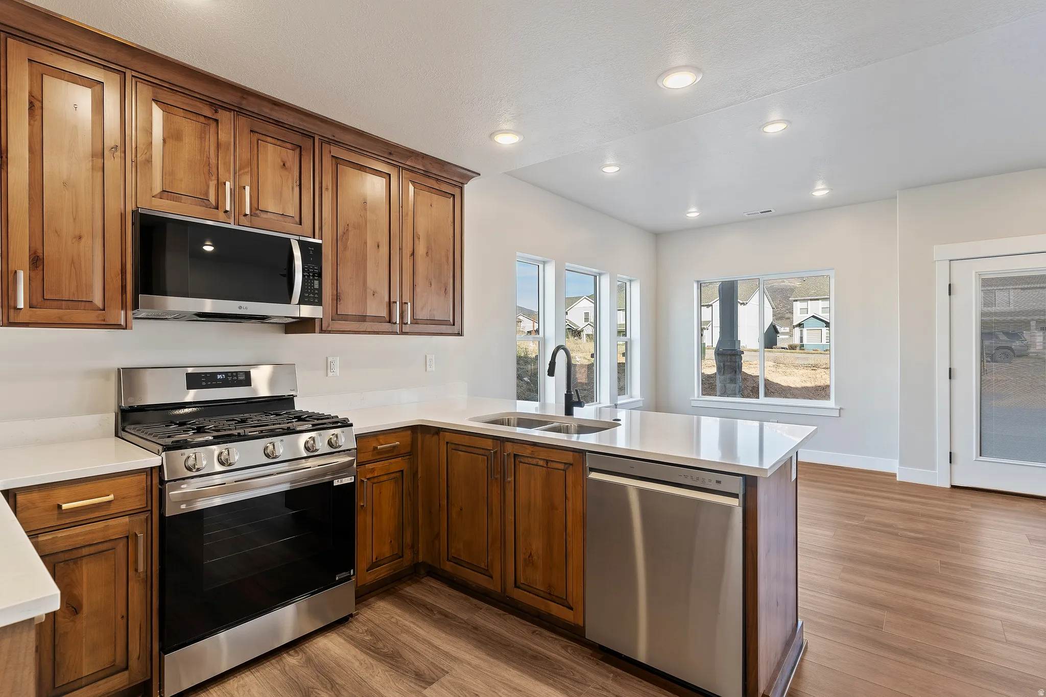 Kitchen featuring wood cabinetry, stainless steel appliances, white countertops, and a black faucet