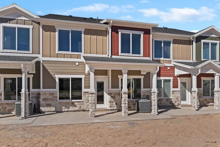 Modern townhomes featuring varied siding colors, stone veneer accents, white trim, and covered entryways