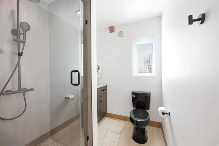 Walk-in shower with clear glass enclosure and matte black fixtures