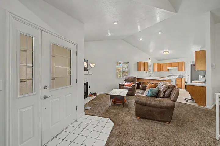 Entryway featuring a white paneled door with frosted glass inserts, tile flooring, and a vaulted ceiling