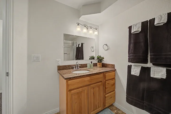 3rd Bathroom vanity with a light wood-finish cabinet, granite-style countertop, and an undermount sink