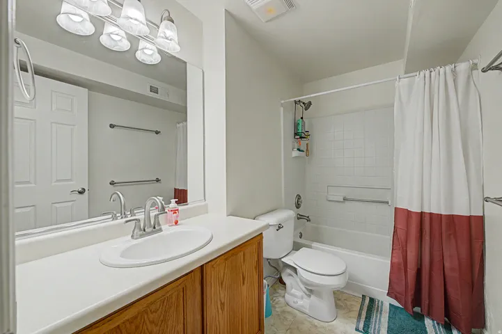 2ns Primary Bedroom Full bathroom featuring a wood-finish vanity with an integrated sink, a large wall mirror, and a shower-tub combination with white tile surround