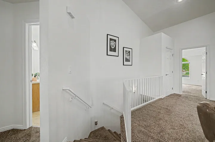 Upper-level hallway featuring a vaulted ceiling and textured carpeting