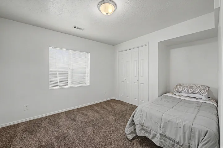 4th bedroom Neutral-toned room featuring a window with blinds, bi-fold closet doors, wall-to-wall carpeting, and an overhead flush-mount light fixture