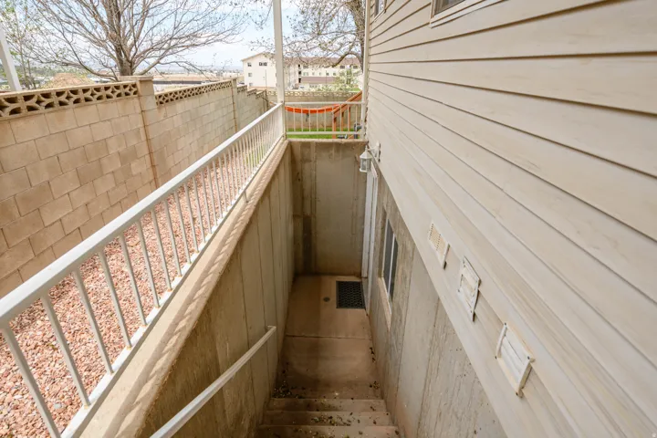 Exterior basement access with concrete stairs and white metal railings