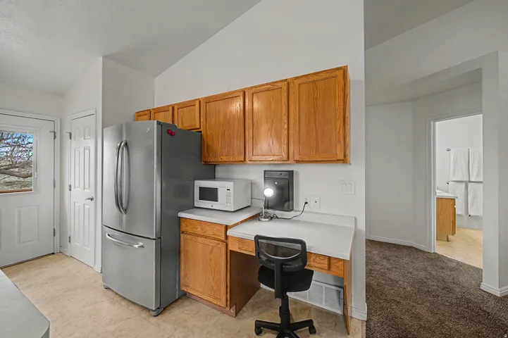 Kitchen area featuring wood-finish cabinetry, light-toned flooring, and a built-in desk space
