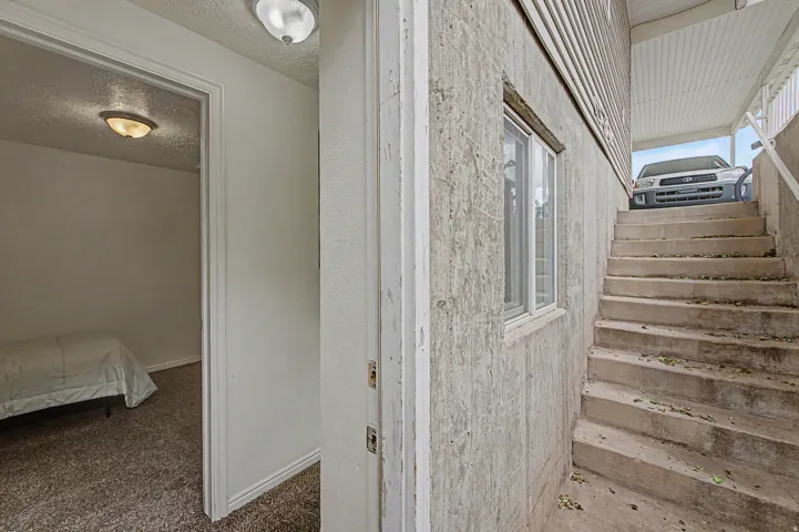 Concrete exterior wall featuring a window with white trim, concrete stairs, and an exterior overhead light fixture