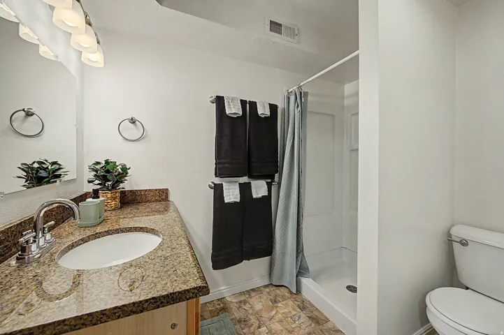 3rd Bathroom featuring a granite-look countertop with an undermount sink, chrome faucet, and a shower with a white surround