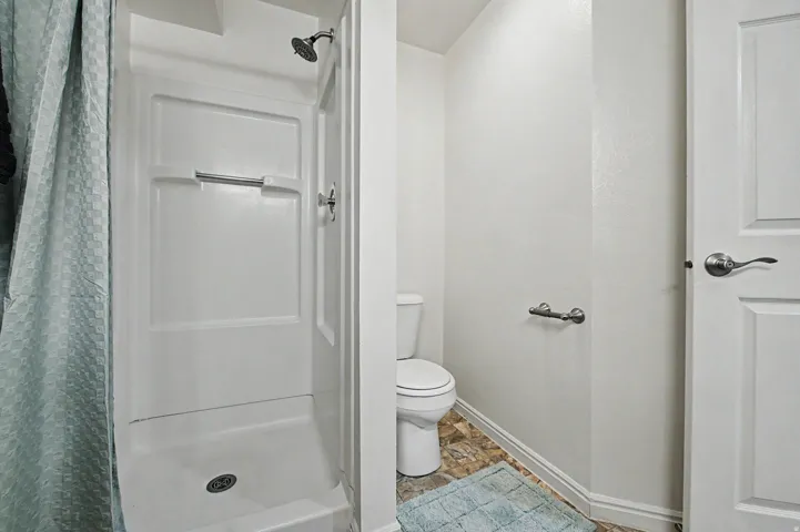 White shower enclosure with a chrome showerhead and control