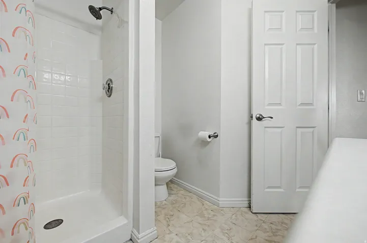 Bathroom featuring a white subway tile shower with a dark finish showerhead and a white toilet
