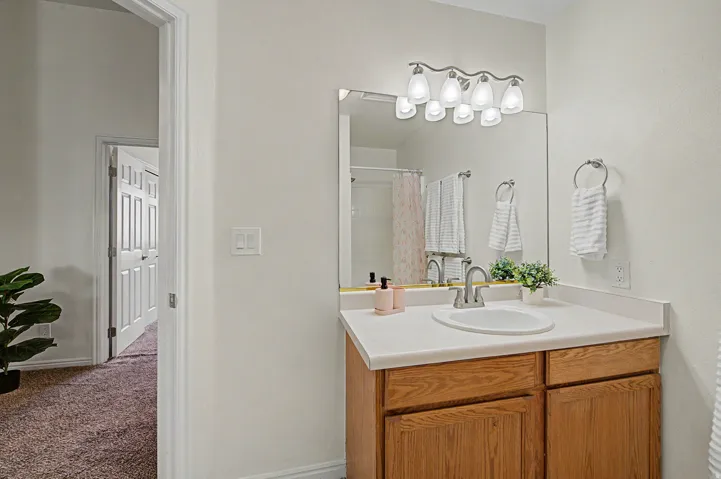 Bathroom vanity featuring a light wood-finish cabinet with double doors, a white countertop, and an integrated white sink