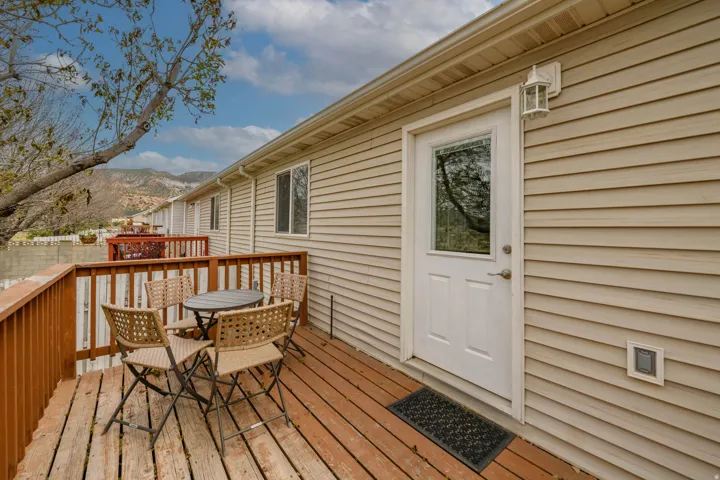 Private deck featuring wood-finish flooring, wood railings, and a solid exterior door with a clear glass panel