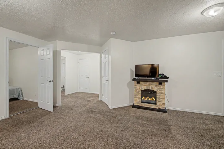 Carpeted room featuring a stone-look electric fireplace with a wood-finish mantel
