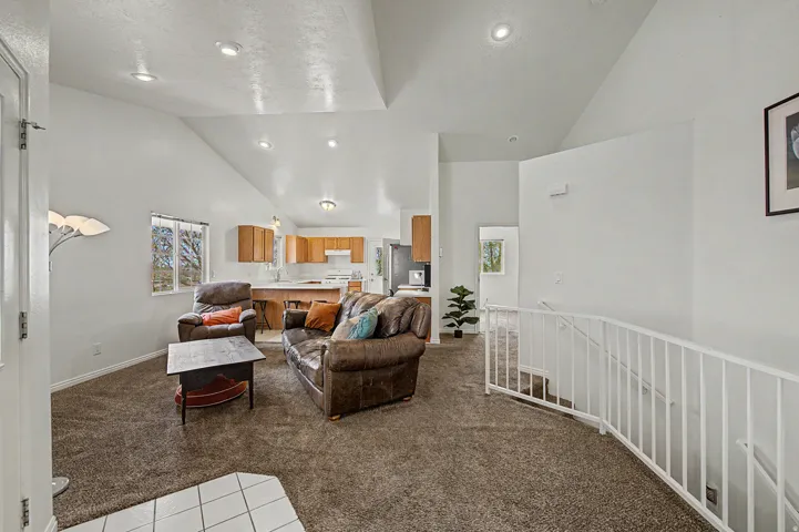 Spacious open-concept living area featuring vaulted ceilings, recessed lighting, and large windows