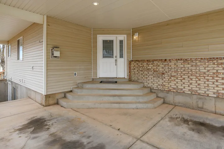 Covered entry with concrete steps and an exterior door featuring decorative glass inserts