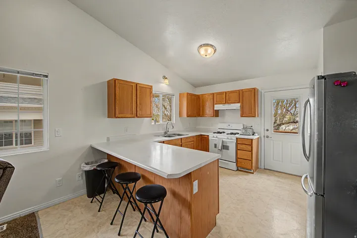 Kitchen featuring light wood cabinetry, white countertops, and a full suite of white appliances including a range and range hood