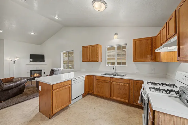 Kitchen featuring wood cabinetry, white countertops, a double basin stainless steel sink, and a four-burner gas range