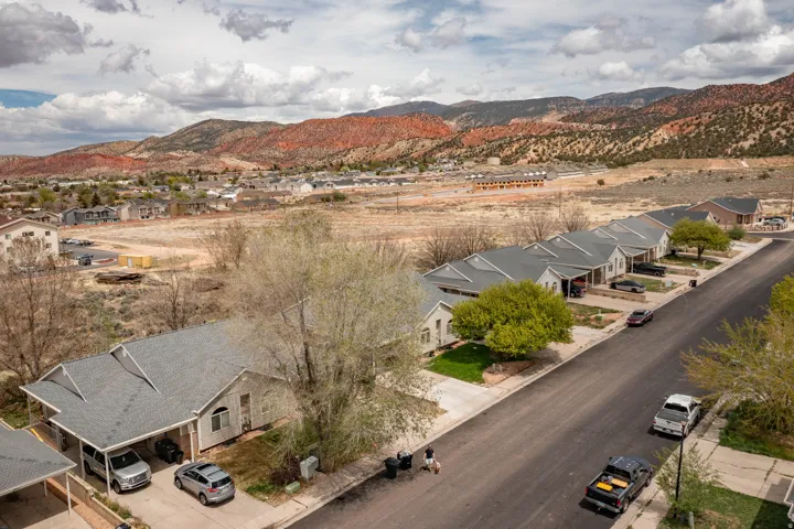 Aerial perspective showcasing a residential street with single-story homes featuring light-colored siding and grey shingle roofs