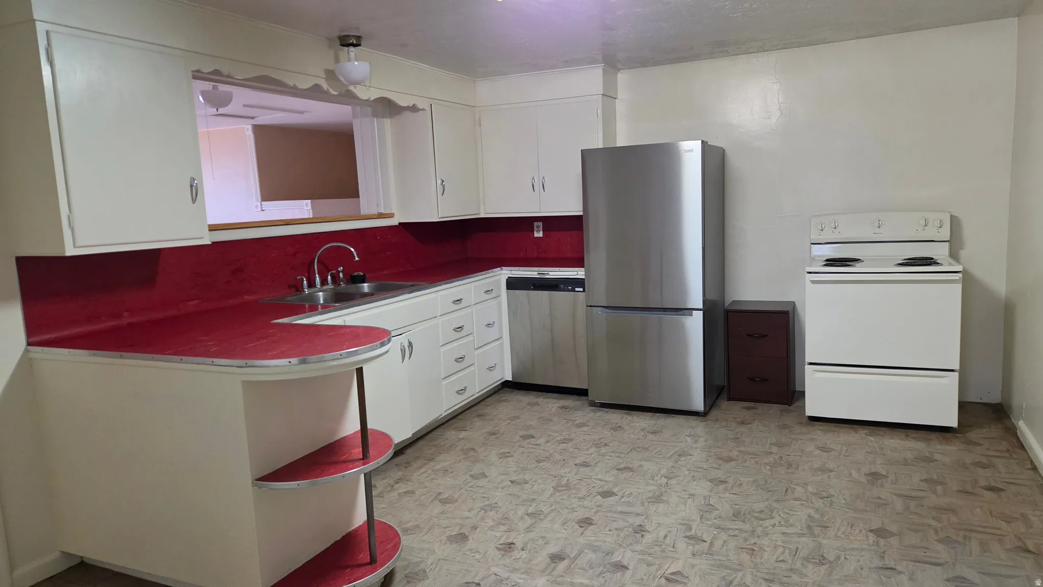 Kitchen featuring white cabinetry, red countertops, and a pass-through window