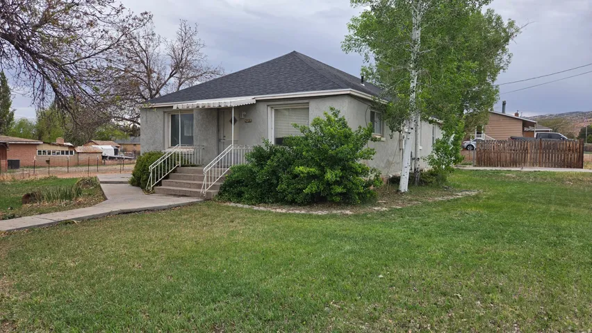 Single-story residence featuring a gray exterior, dark shingle roof, and a front entry with concrete steps and white railings
