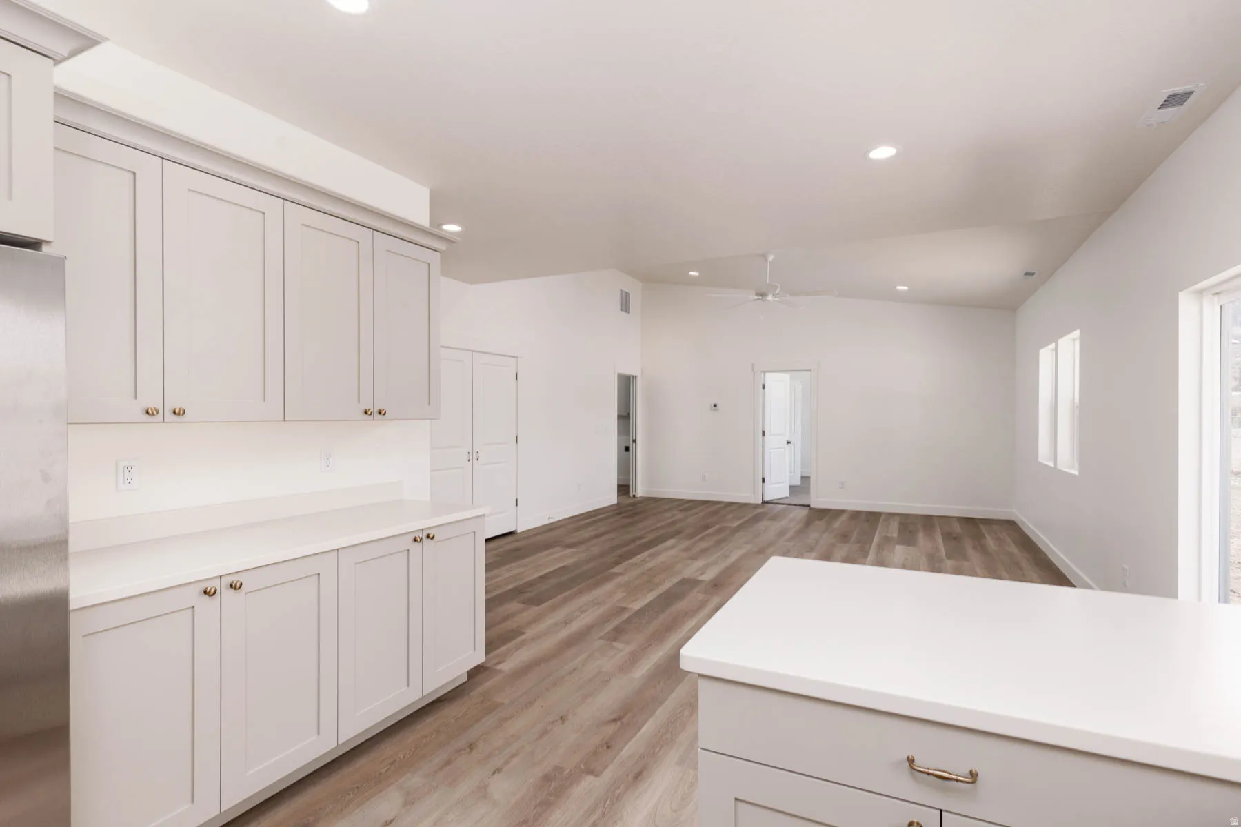Kitchen featuring light gray cabinetry with gold-toned hardware, white countertops, and stainless steel appliances