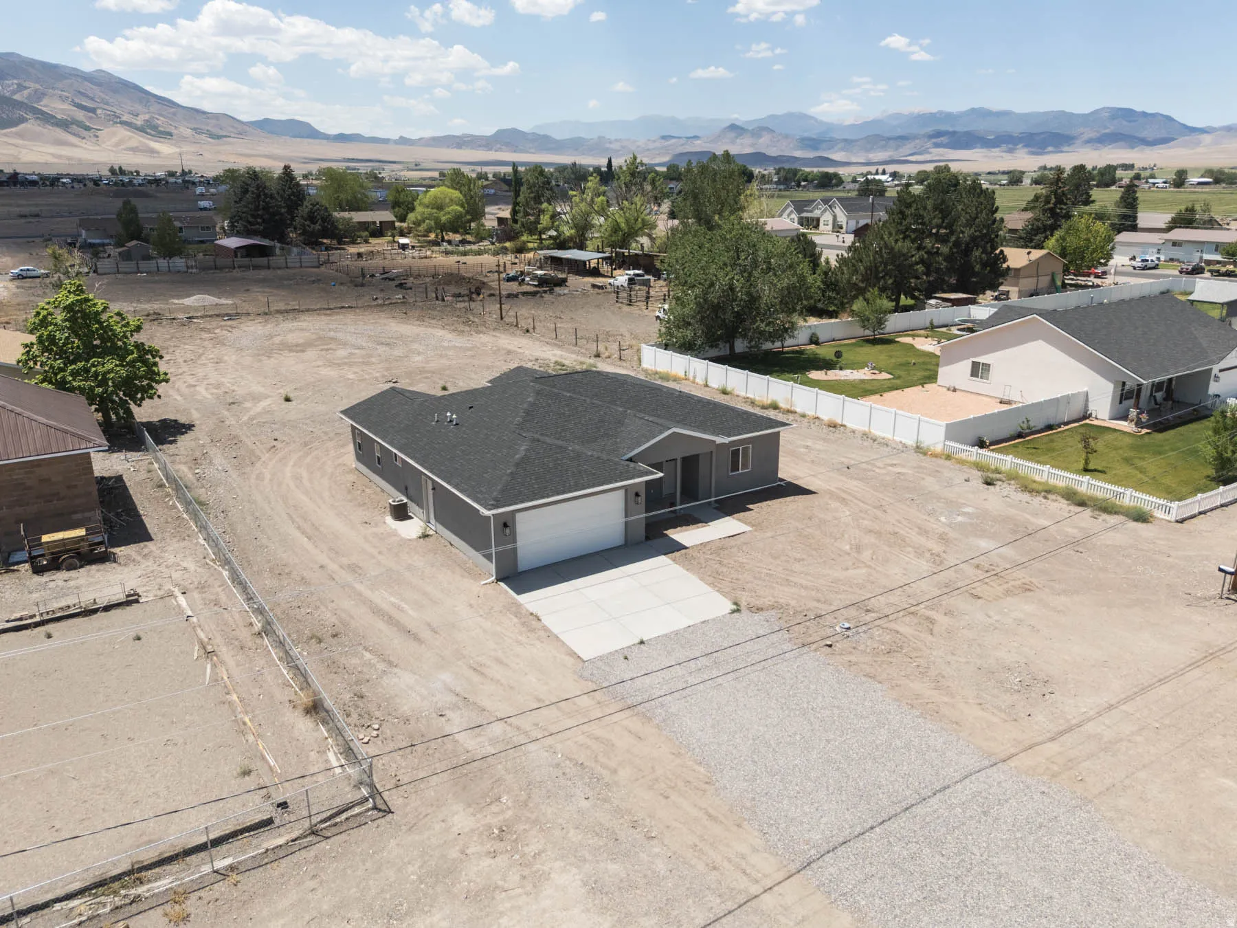 Contemporary single-story residence featuring a dark gray exterior, a two-car garage with a white door, and a paved concrete driveway