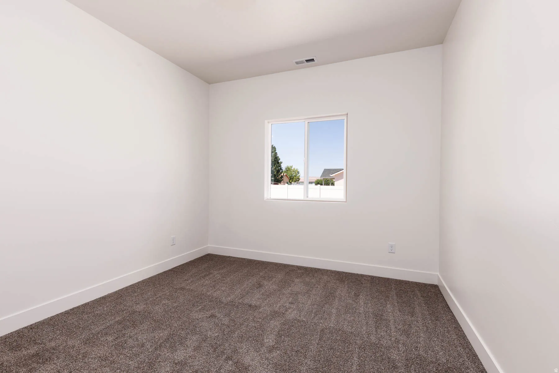 Neutral white walls complementing dark gray carpeting, trimmed with white baseboards