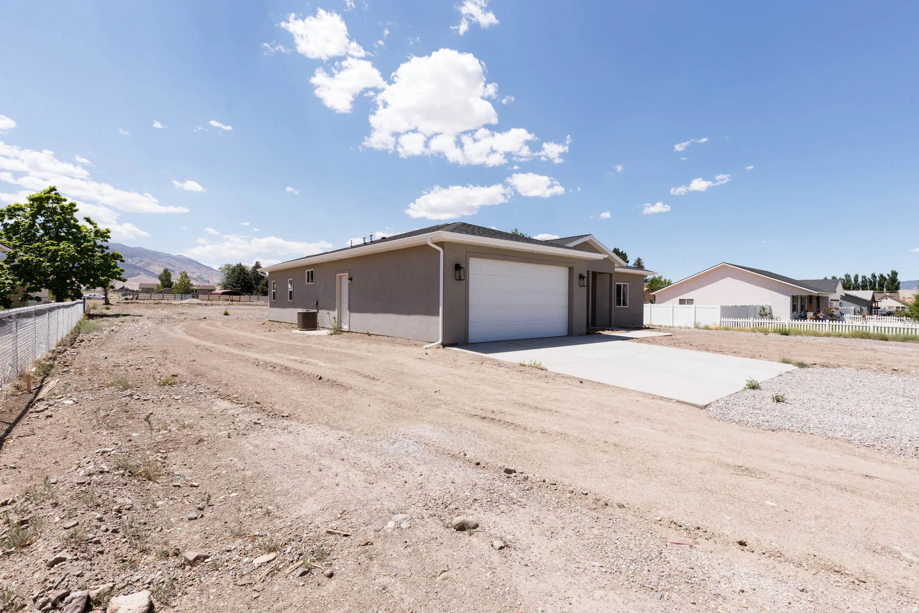 Contemporary ranch-style residence featuring a two-car garage, stucco exterior, and concrete driveway