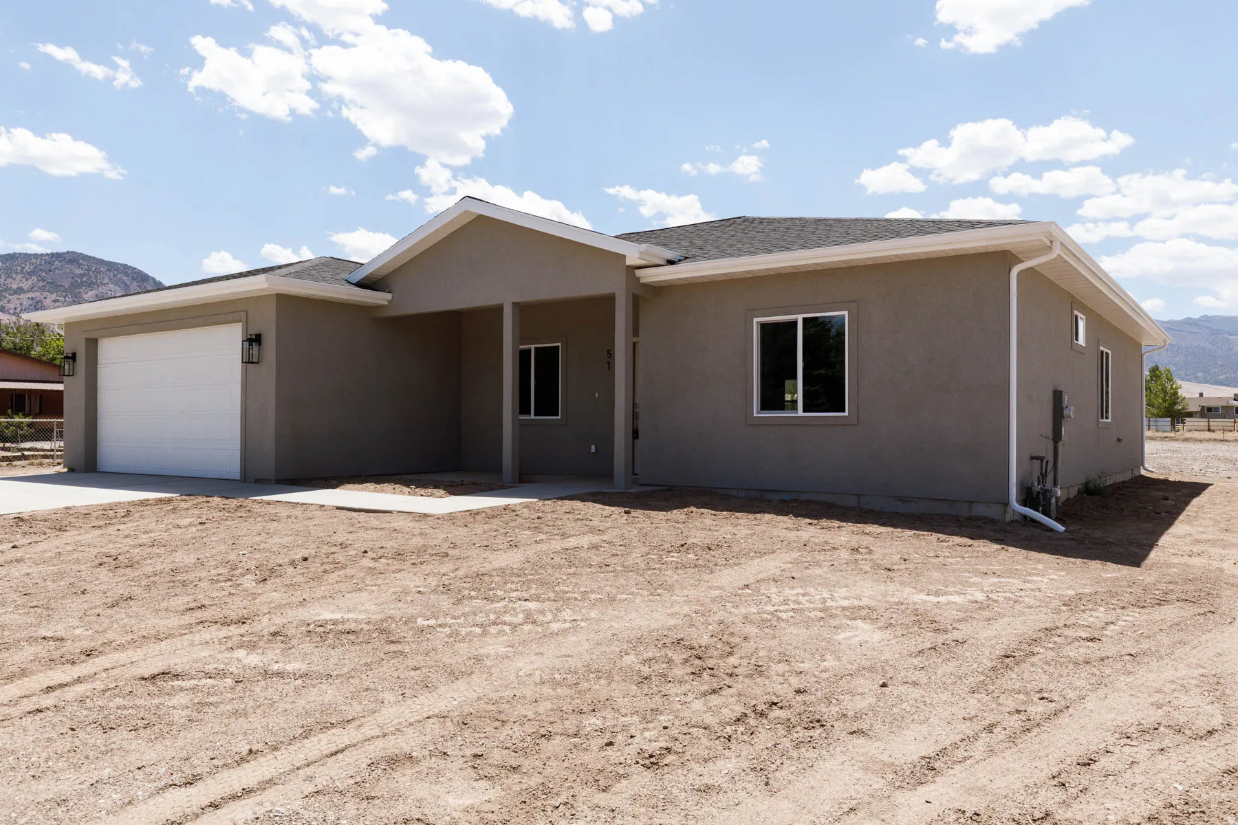 Stucco exterior with an attached garage, covered entryway, double-pane windows, and a dark shingle roof