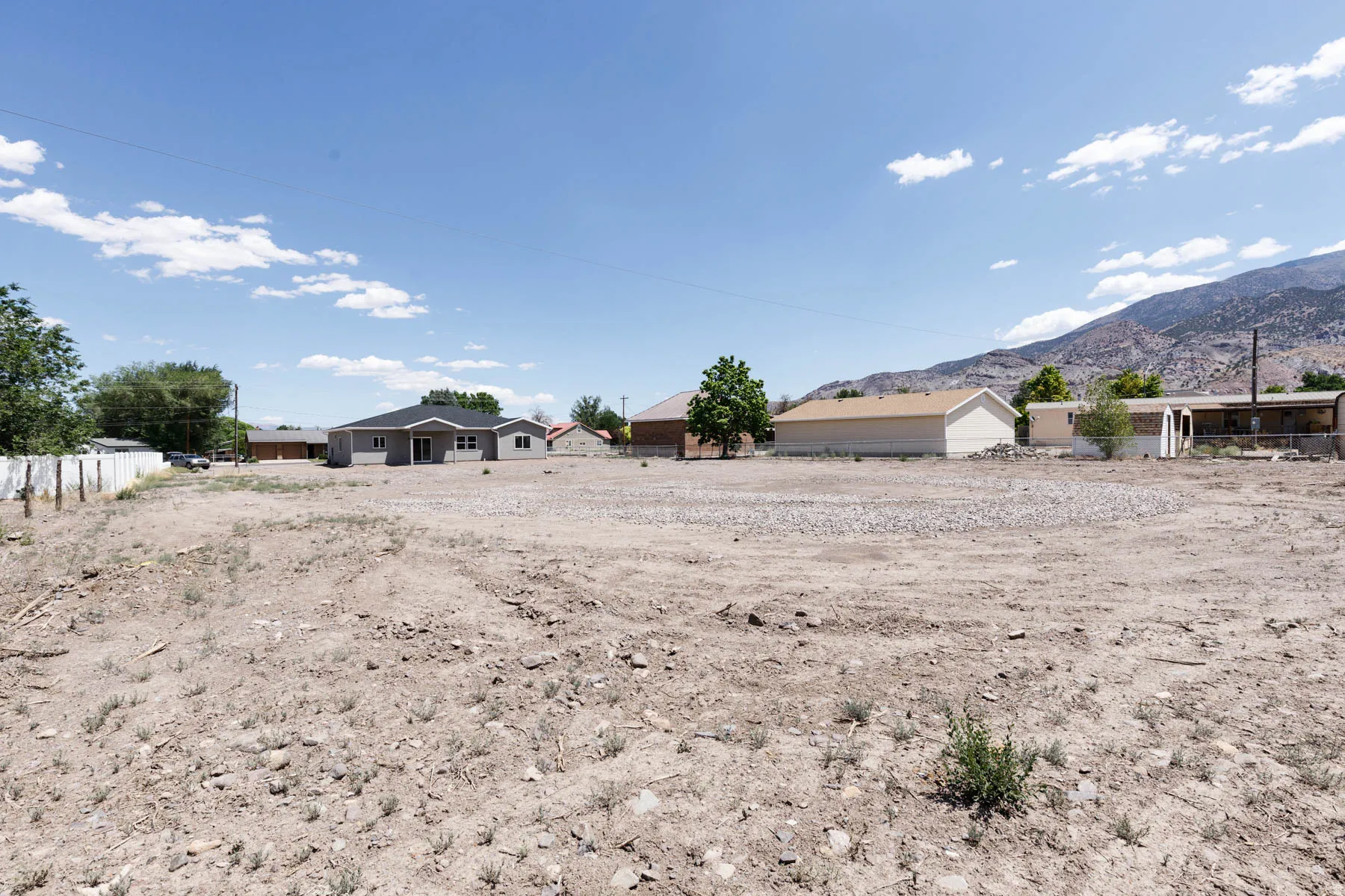 Expansive undeveloped lot featuring a level terrain with scattered small rocks and sparse natural vegetation