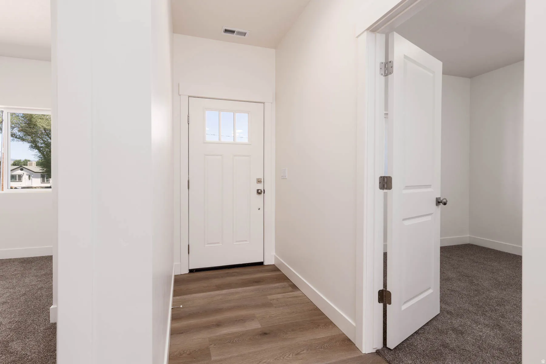 Entryway featuring a white door with window panes, wood-finish flooring, and white baseboards