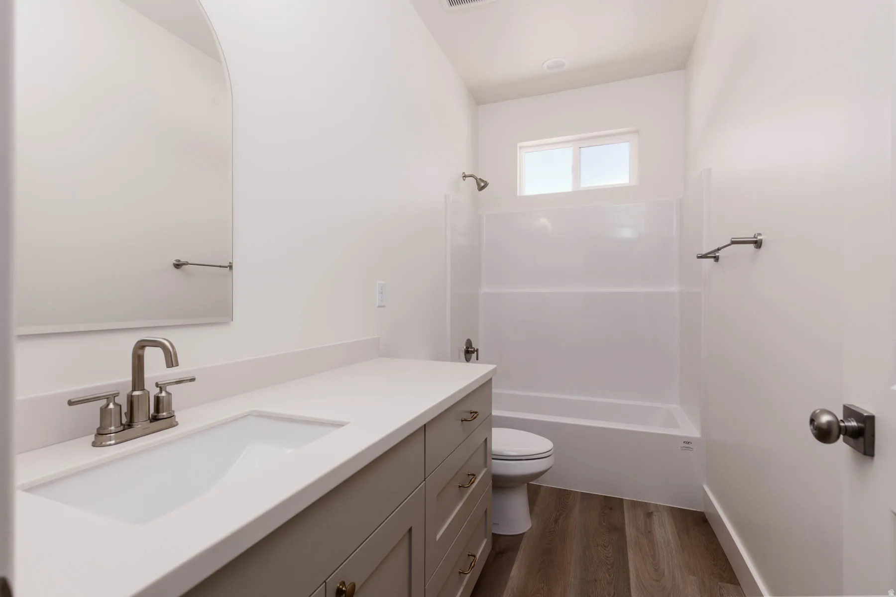 Neutral-toned vanity with an integrated sink and brushed nickel faucet, set against white walls