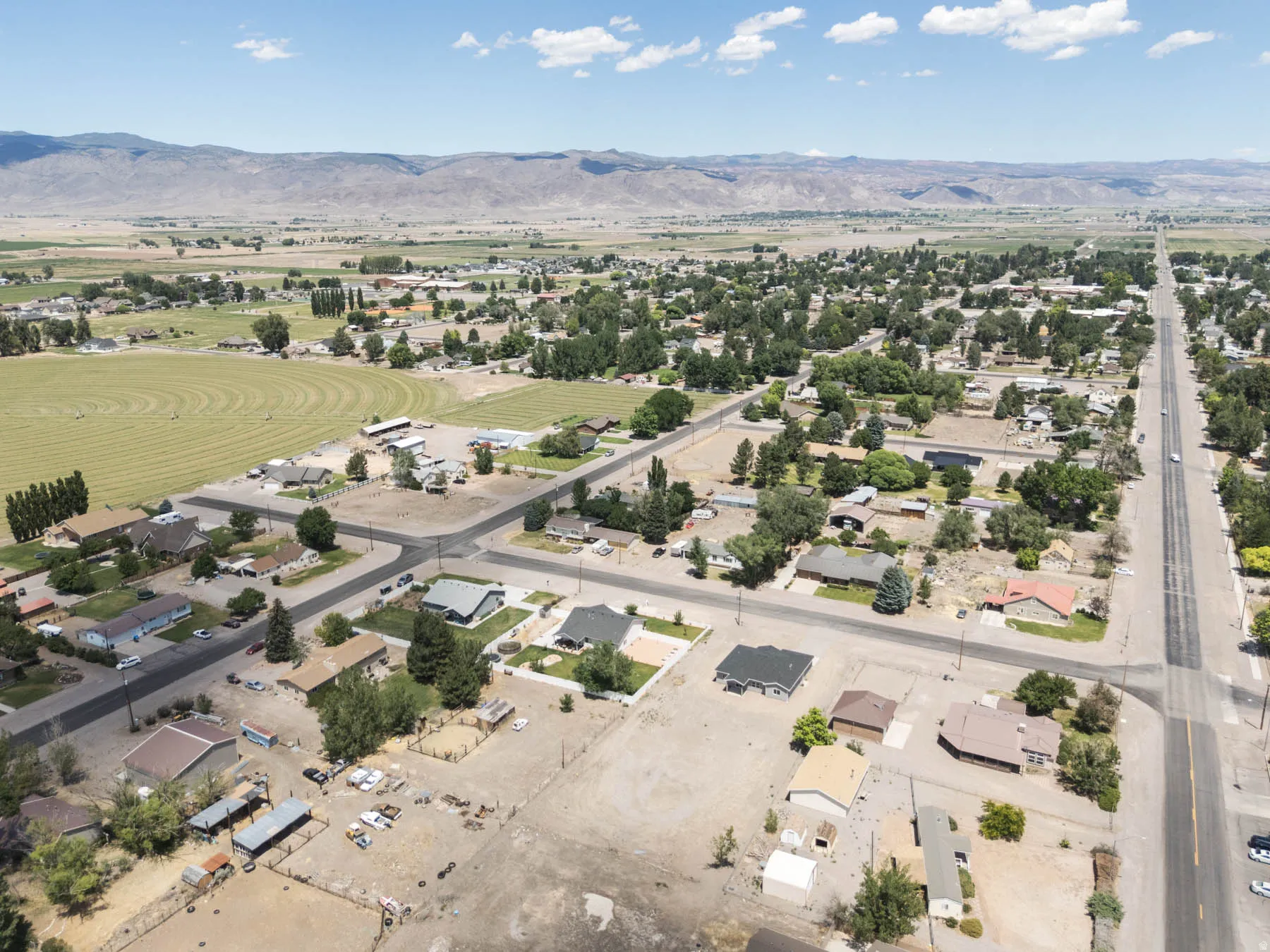 Aerial perspective showcasing a community with diverse residential properties, expansive open land, and established roadways