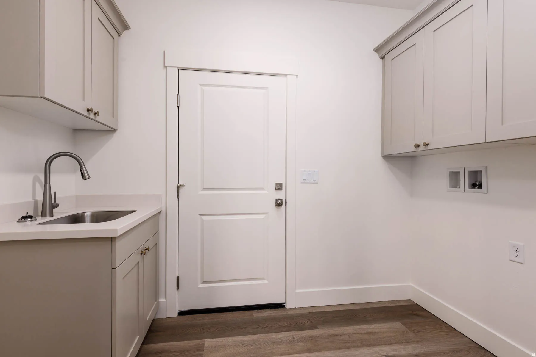 Functional utility room featuring wood-finish flooring and white walls