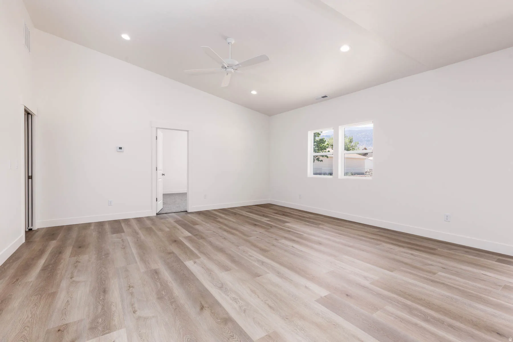 Spacious room featuring wood-finish flooring, vaulted ceilings, and recessed lighting