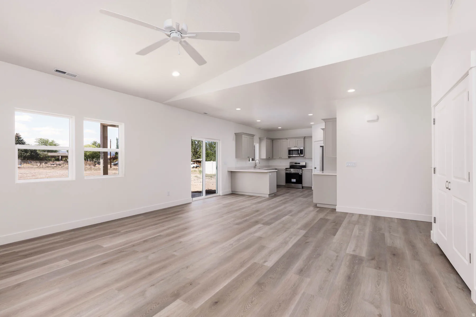Open-concept living area featuring light wood-finish flooring and a contemporary ceiling fan