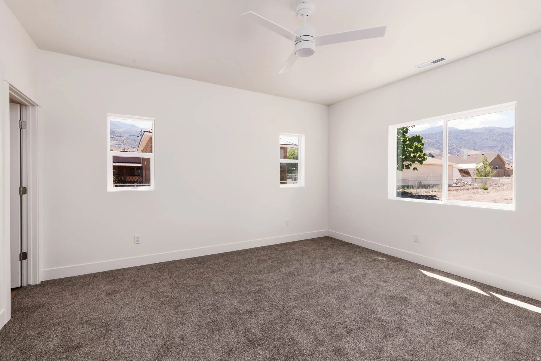 Spacious room with gray textured carpeting, white walls, and white baseboards