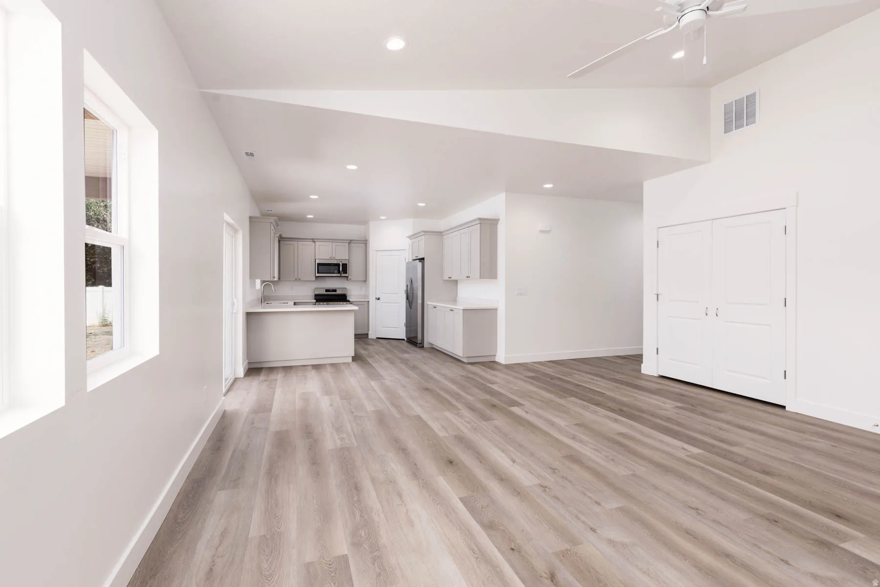 Open-concept living space with wood-finish flooring, vaulted ceilings, and recessed lighting