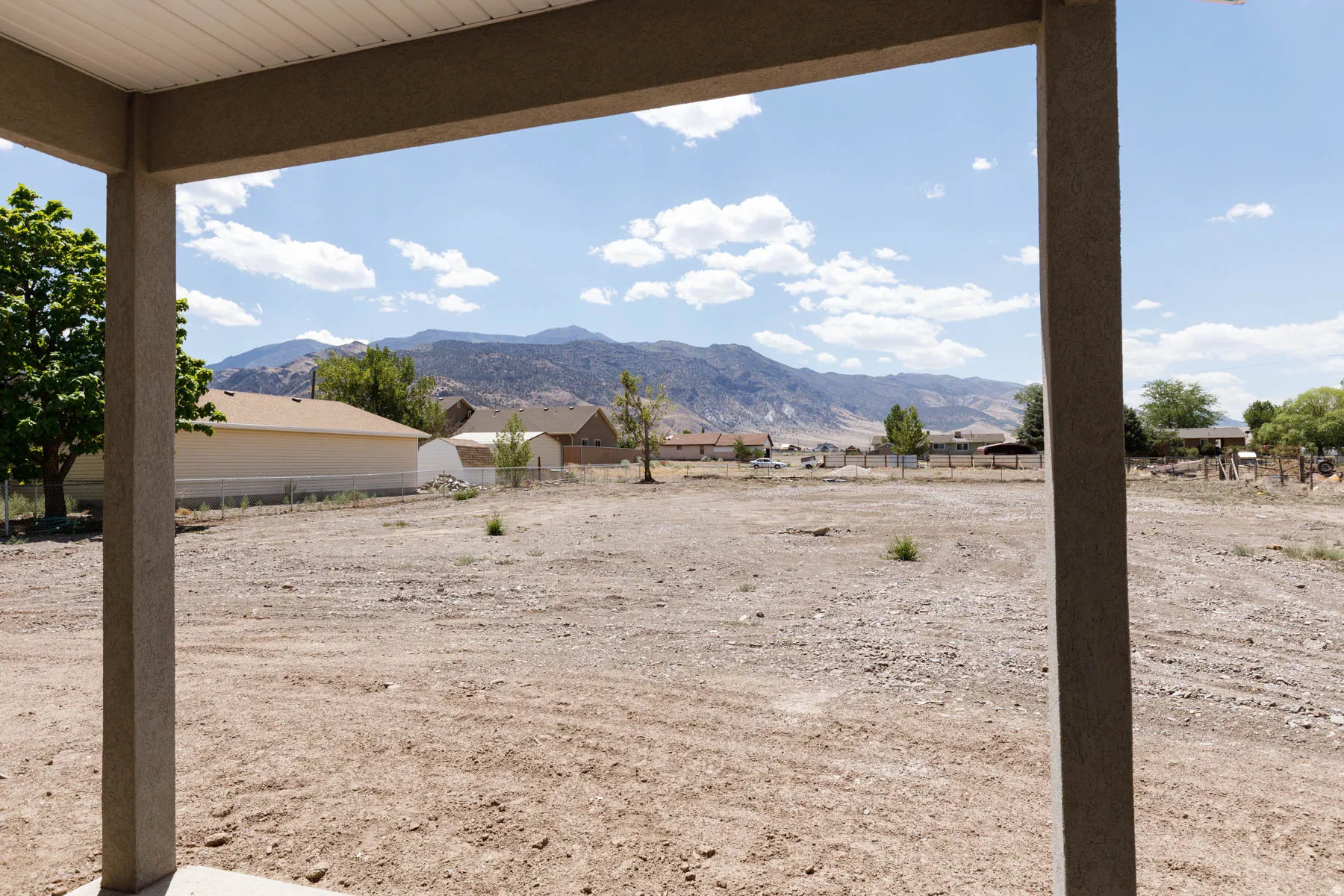 Spacious uncovered patio with structural columns, offering expansive views of surrounding mountains