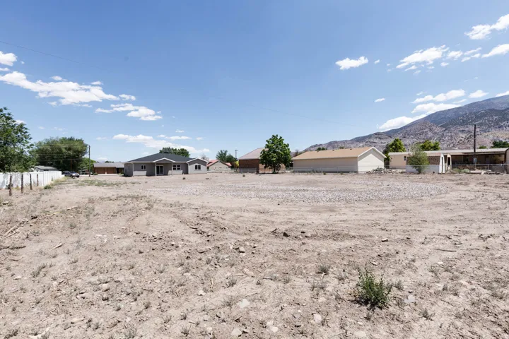 Expansive undeveloped lot featuring a level terrain with scattered small rocks and sparse natural vegetation