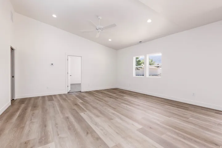 Spacious room featuring wood-finish flooring, vaulted ceilings, and recessed lighting