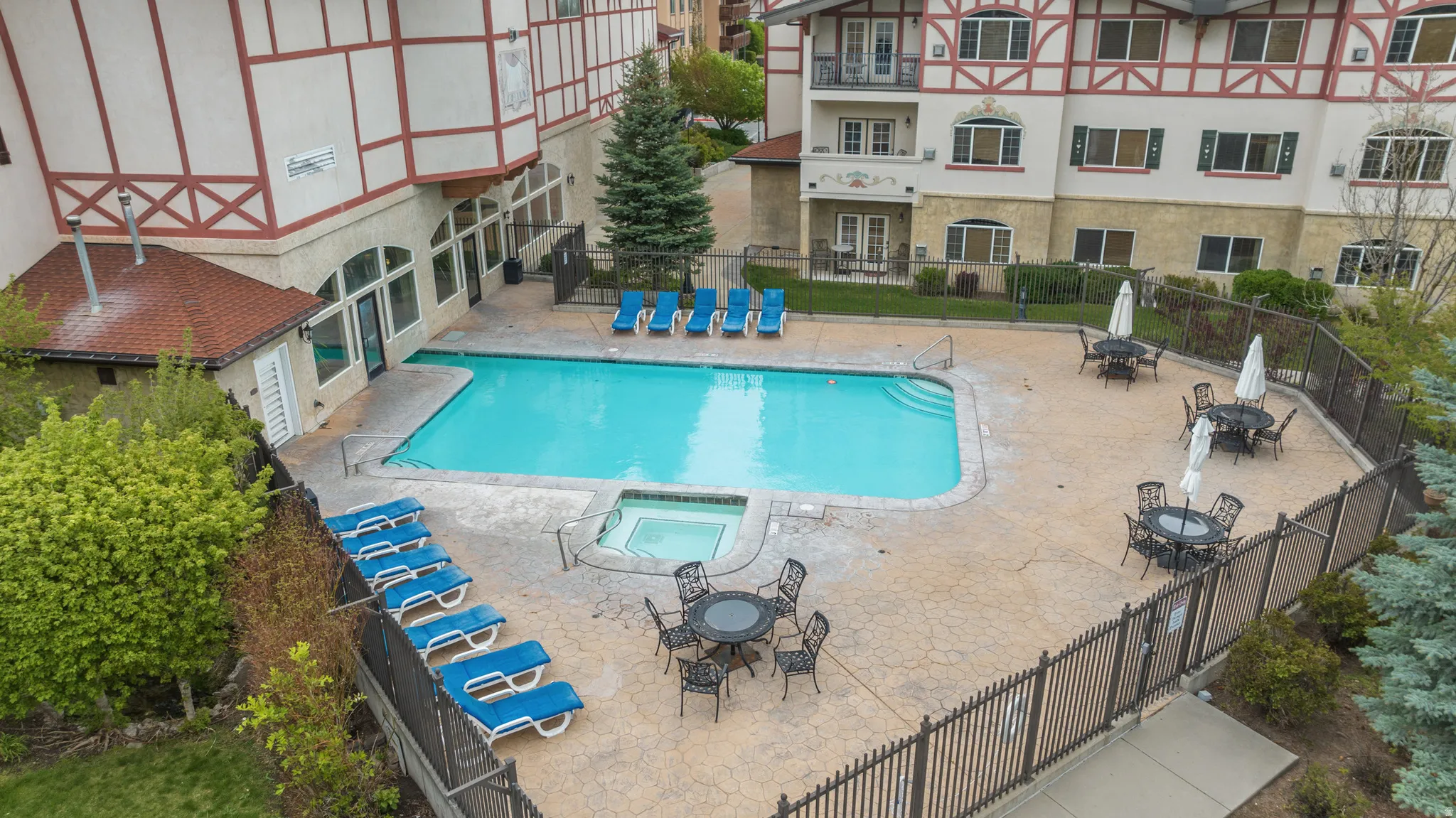 Outdoor swimming pool with integrated spa, surrounded by a textured concrete patio