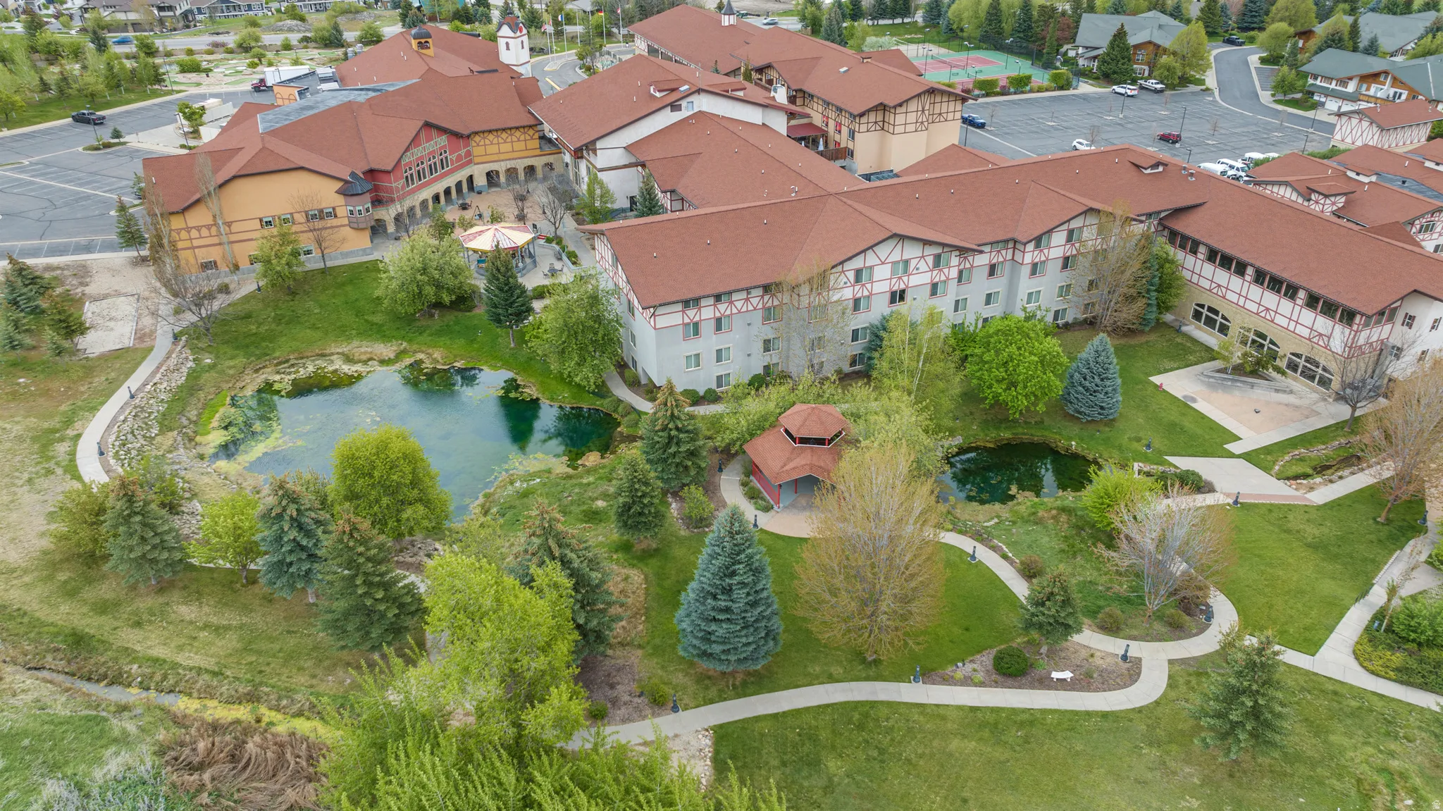 Expansive grounds featuring multiple ponds, mature trees, manicured lawns, a gazebo, and winding pathways
