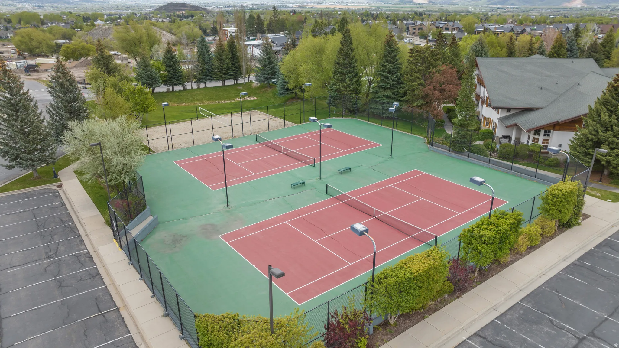 Two full-size tennis courts with red playing surfaces and green surrounds