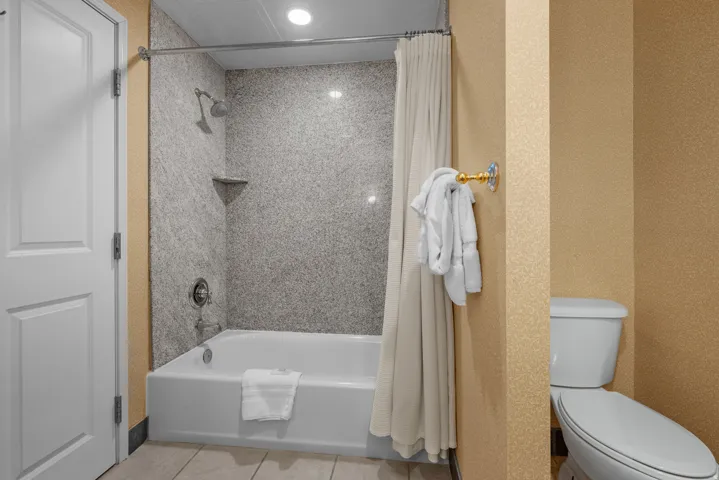 Bathroom featuring a white bathtub, integrated shower, and textured shower surround