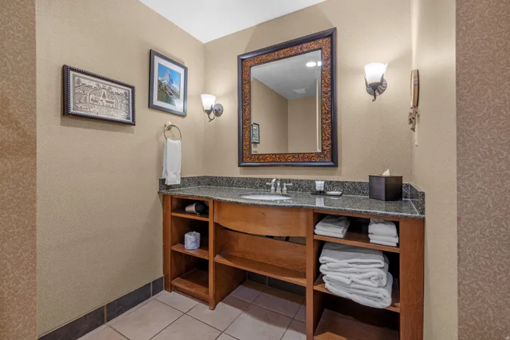 Vanity featuring a polished stone countertop, integrated sink, and an ornamental framed mirror