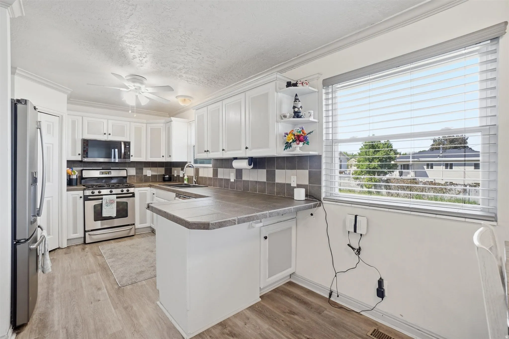 Bright kitchen featuring white cabinetry, stainless steel appliances, and wood-finish flooring