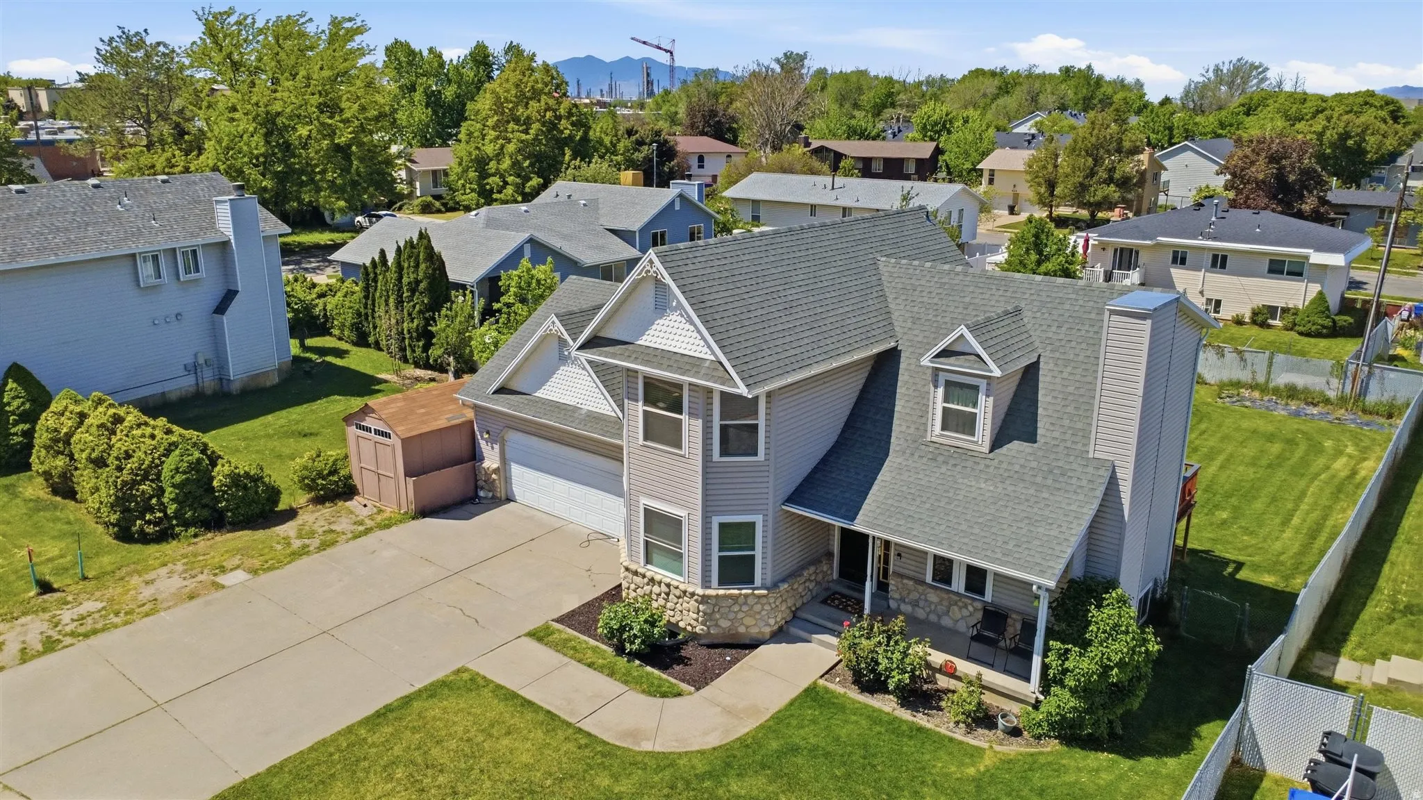 Two-story residence featuring light gray siding with white trim accents and a stone veneer foundation